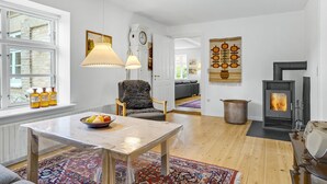 Una sala de estar moderna con chimenea, una mesa de comedor con fruta y un sillón acogedor.