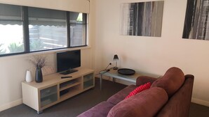A living room with a TV, a sofa, a coffee table, and artwork on the walls.
