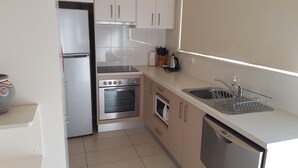 A compact kitchen with a refrigerator, oven, microwave, and dishwasher.