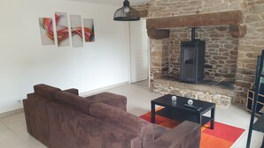 A living room with a stone fireplace, a brown sofa, and a black coffee table with decorative items.