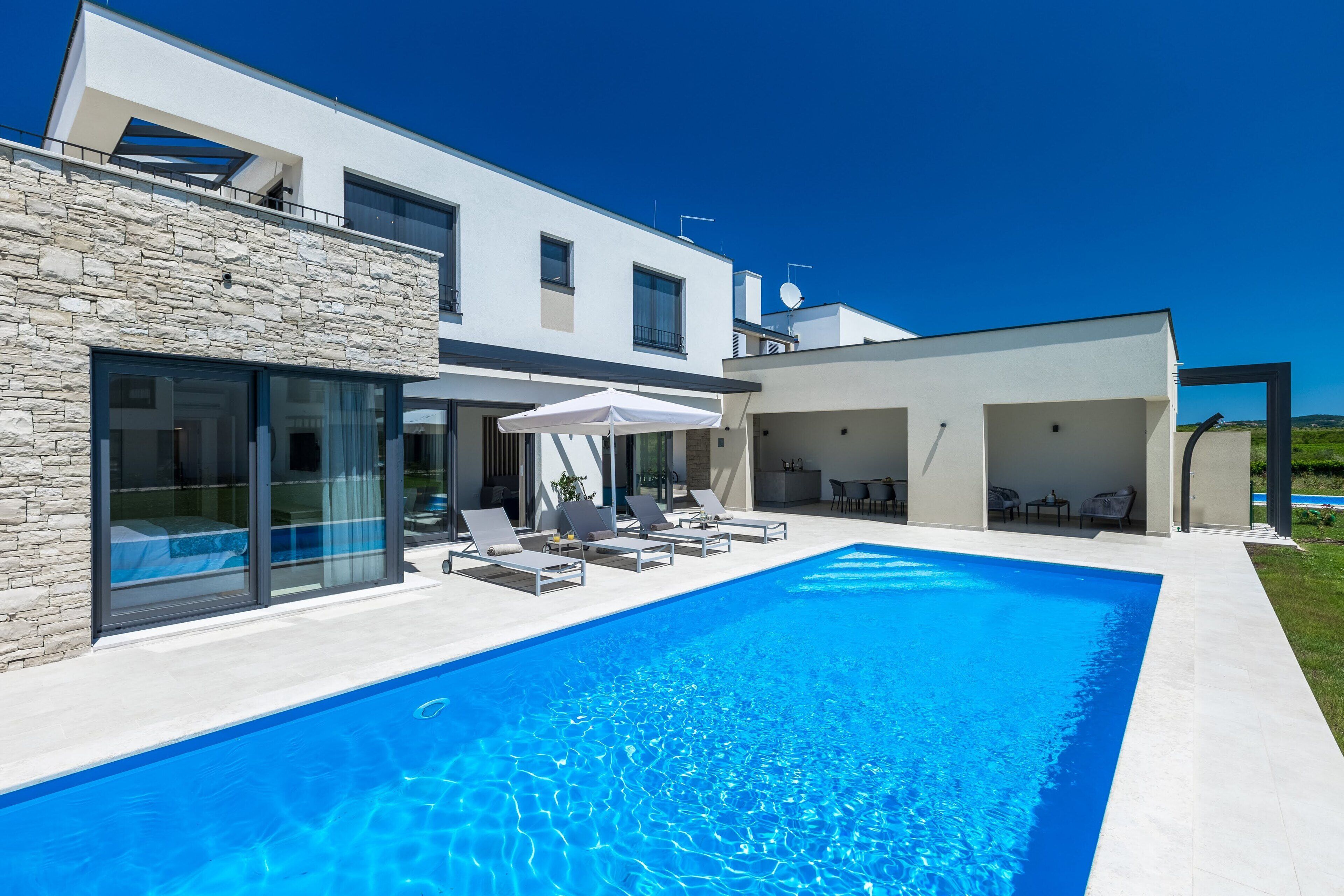 A modern house with a swimming pool, large windows, and outdoor seating.