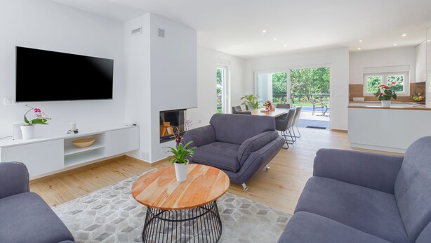 Una sala de estar moderna con un televisor de pantalla plana, sofás grises, una mesa de centro de madera y una chimenea.