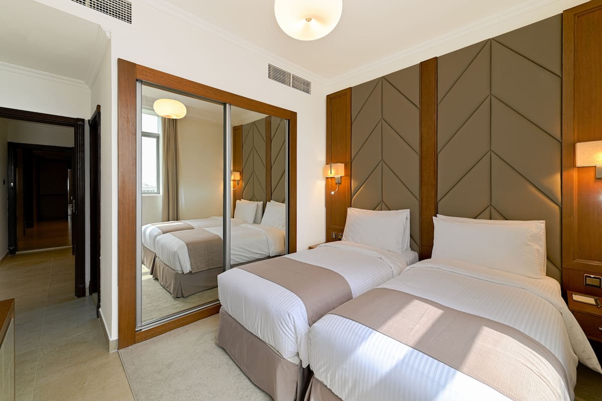 Ein Hotelzimmer mit zwei Betten, einem großen Spiegel und einem hölzernen Kopfteil.