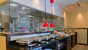 A buffet area with multiple serving stations, glass display cases, and red pendant lights. - TIME Moonstone Hotel Apartments (Al-Fujairah)