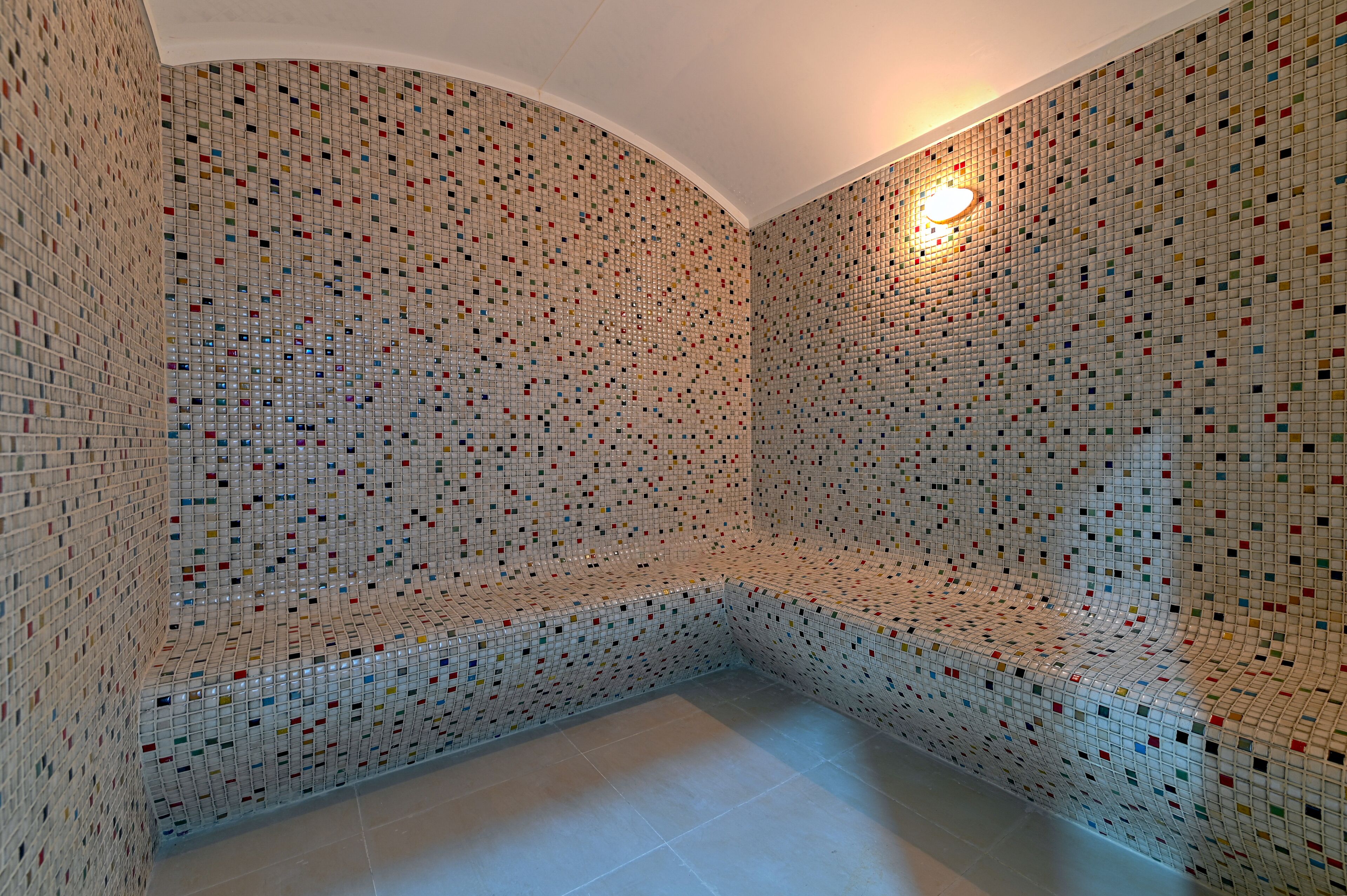 A room with a unique mosaic tile wall and a curved ceiling.