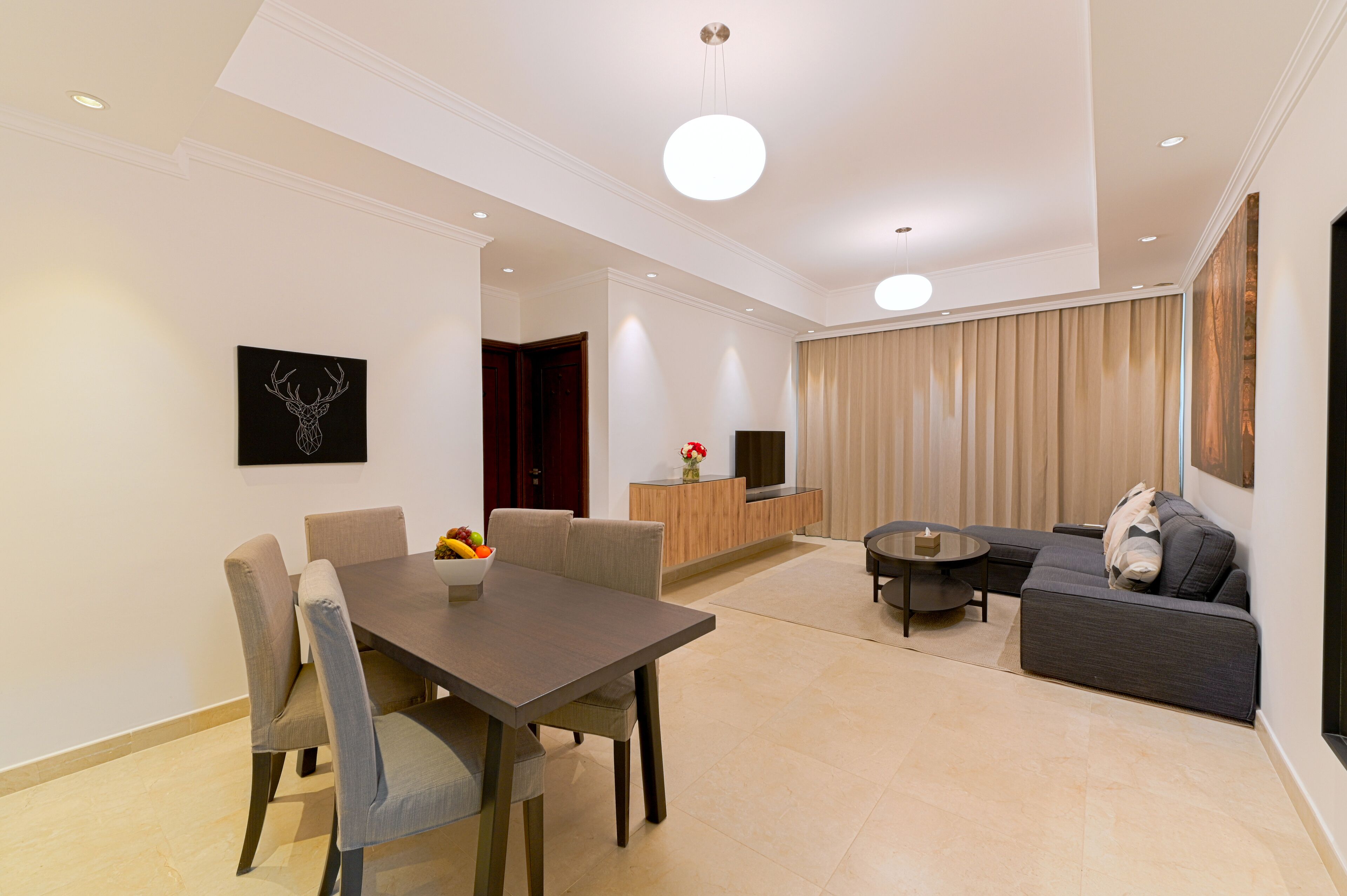 A modern living room with a dining area, a sofa, and a TV.