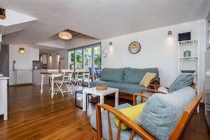 A spacious living area with a grey sofa, wooden chairs, a small table, and a kitchen in the background. - Villa Ferenc Zadarvillas (Rovinj)