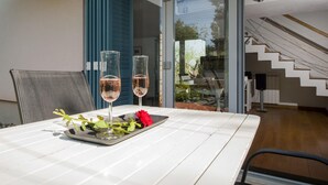 A dining table with two glasses of rosé wine, a red rose, and a small plate. - Villa Ferenc Zadarvillas (Rovinj)