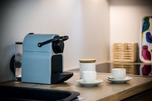 A Nespresso coffee machine on a wooden counter with a water reservoir, a white cup, and a saucer. - Villa Ferenc Zadarvillas (Rovinj)