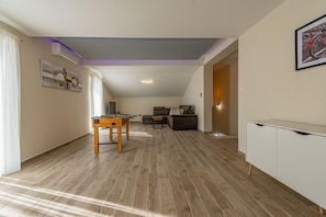A spacious living area with a wooden floor, a sofa, a coffee table, and a cabinet.