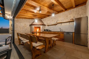 A rustic kitchen with a stone wall, wooden ceiling, and a built-in oven.