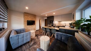 A modern kitchen with a central island, bar seating, and a flat-screen TV mounted on a brick wall. - Radvanice Kcg351 in Radvanice (Radvanice)