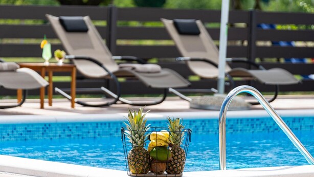 A poolside area with lounge chairs and a fruit basket. - Villa Silentium Zadarvillas (Benkovac)