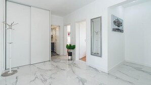 A hallway with white walls, a marble floor, a coat rack, a potted plant, and a framed picture. - Villa Silentium Zadarvillas (Benkovac)