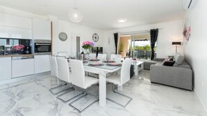 A modern kitchen with white cabinets, a built-in oven, and a dining area with a glass table and white chairs. - Villa Silentium Zadarvillas (Benkovac)