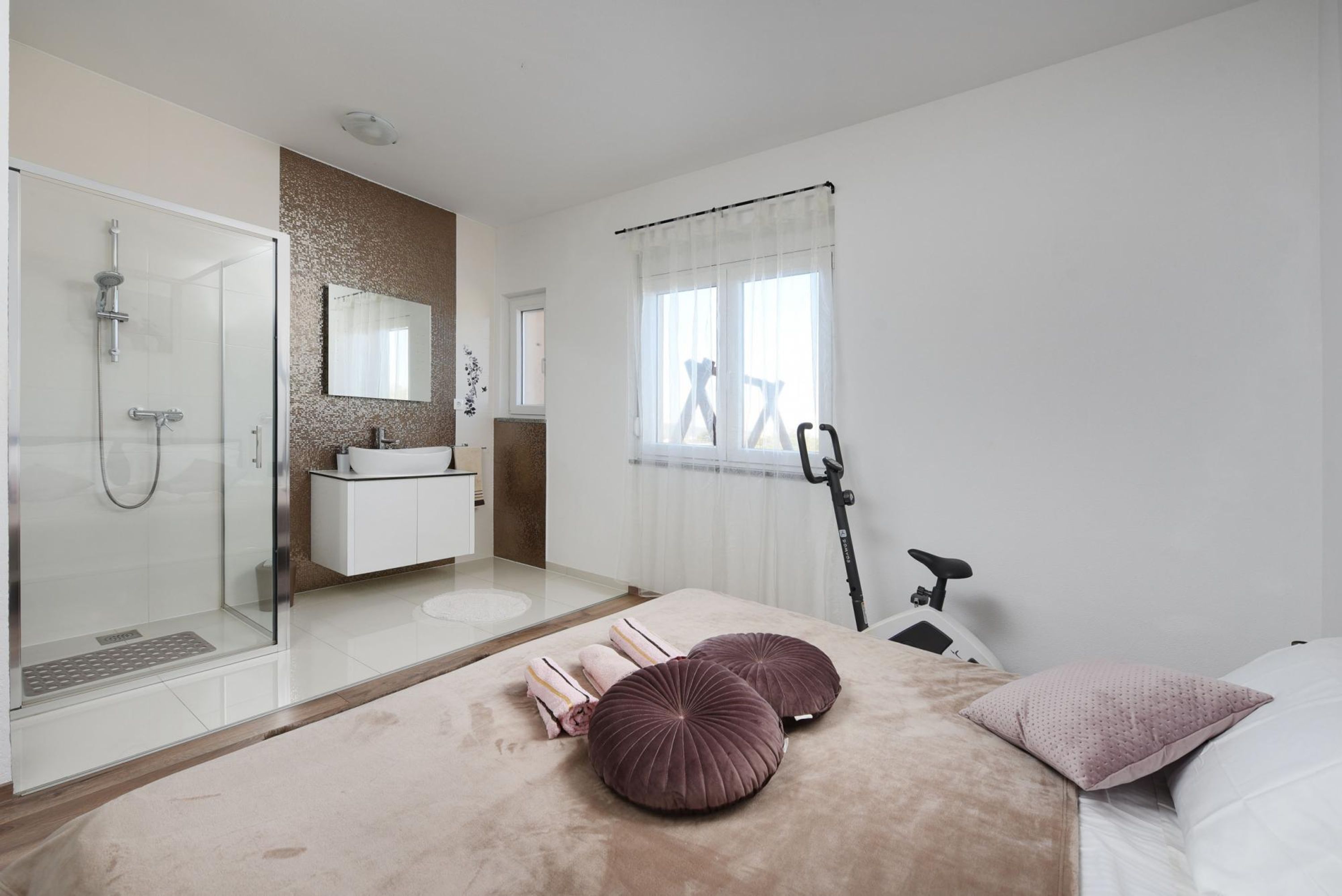 Un bagno moderno con doccia in vetro, lavandino bianco e uno specchio grande.