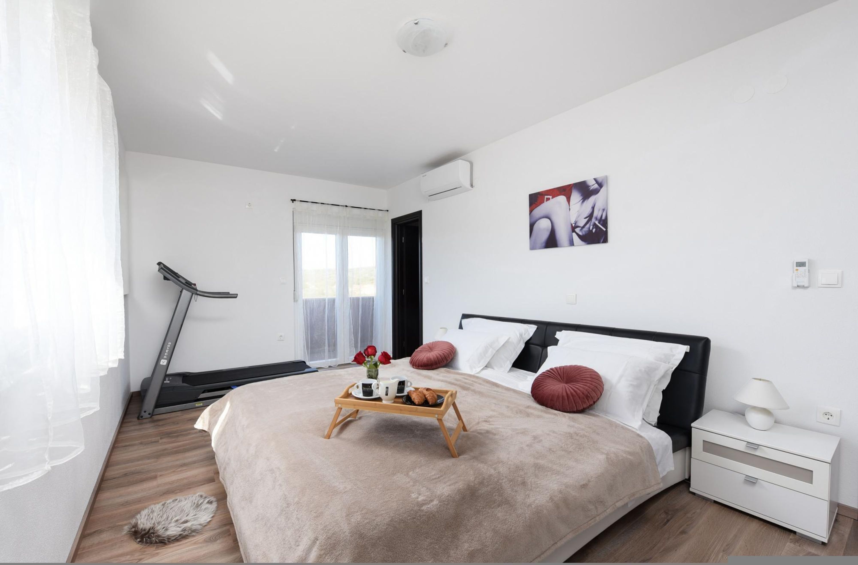 A modern bedroom with a bed, bedside table, and a treadmill.