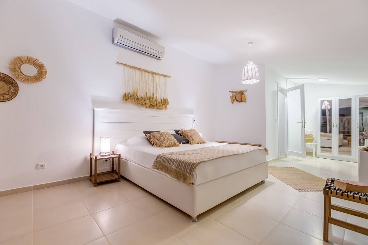 Un dormitorio con cama, mesita de noche y un adorno macramé en la pared.