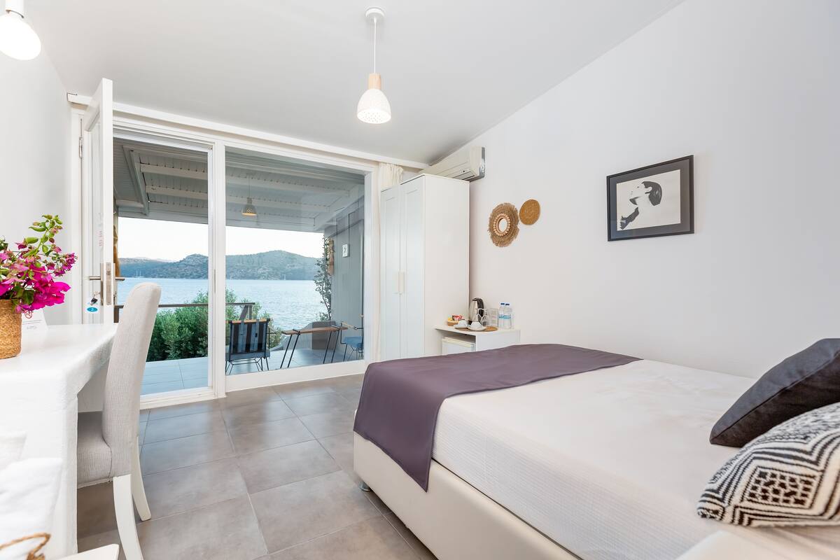 Un dormitorio con cama, escritorio y vista al mar.
