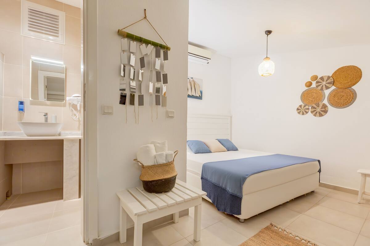 Un baño moderno y limpio con lavamanos blanco, espejo y lámpara colgante.