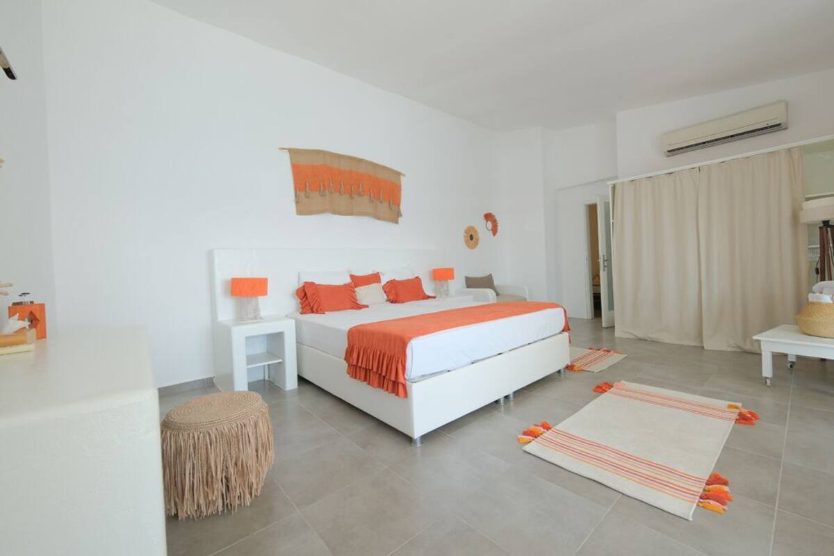 Un dormitorio moderno con una cama grande, mesitas de noche, un espejo y una ventana con cortinas.