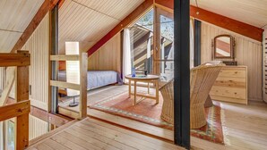 A cozy attic bedroom with a sloped ceiling, wooden beams, a bed, a dresser, a chair, and a small table. - 2 bedroom cozy home in Dronningmølle (Dronningmølle)