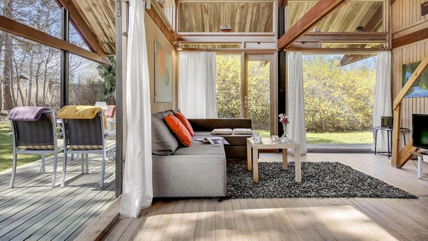 A modern, open-plan living area with a sofa, coffee table, and a view of the outdoors. - 2 bedroom cozy home in Dronningmølle (Dronningmølle)