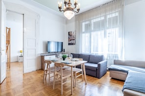En moderne stue med spiseplads, en sofa og et fjernsyn.