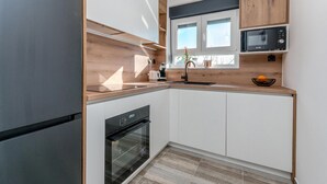 Moderni keittiö, jossa on sisäänrakennettu uuni, mikroaaltouuni ja pesuallas.