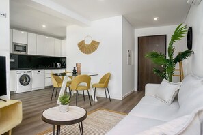 A modern living room with a sofa, a coffee table, and a dining area with chairs.