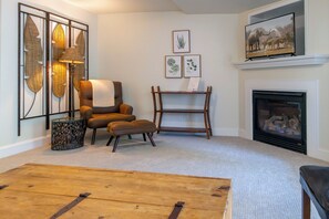 Una sala de estar con chimenea, un sofá, una mesa de centro y decoración en la pared.