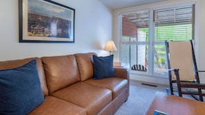 Ein Wohnzimmer mit braunem Ledersofa, einer Lampe, einem gerahmten Bild und einem Sessel.