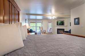 Un dormitorio con una cama grande, chimenea, televisor y ventilador de techo.
