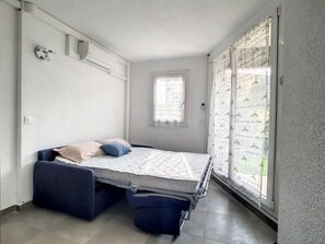 A compact room with a bed, a window, and a curtain.