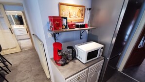 Eine kleine Küche mit Mikrowelle, Kaffeemaschine und einer Ablage für Küchenutensilien.