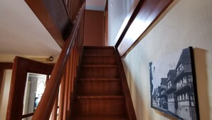 Eine Holztreppe mit Handlauf, die zu einer Plattform führt, auf der ein schwarz-weißer Rahmen um ein Foto ist.