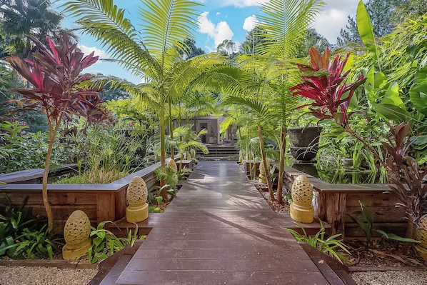 Un sentiero costeggiato da piante tropicali che conduce a un edificio.
