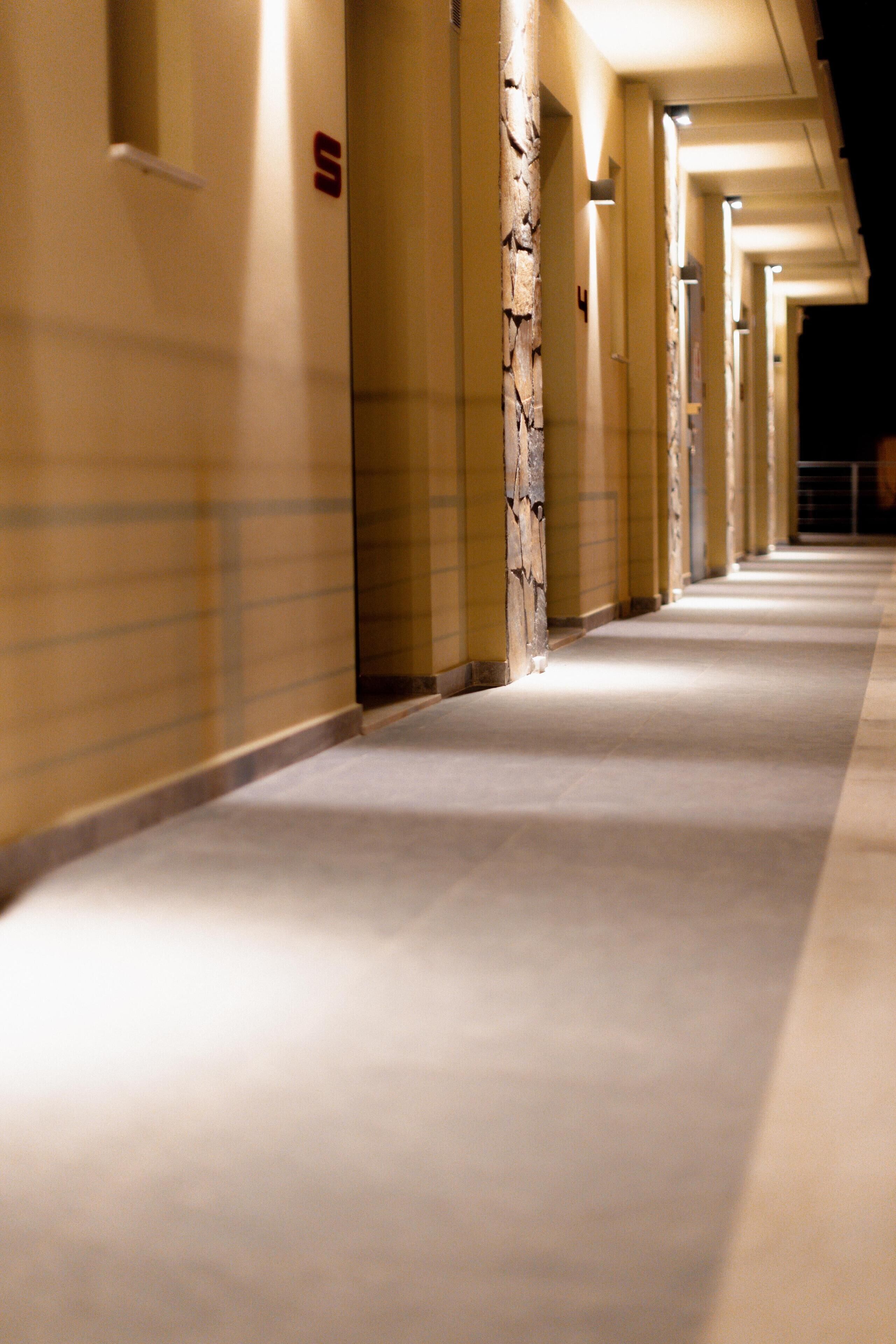 A long, well-lit hallway with uniform doors and a clean, tiled floor.