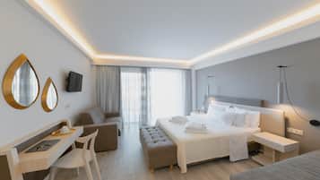 A modern hotel room with a bed, a desk, a chair, a sofa, and a large window with curtains.