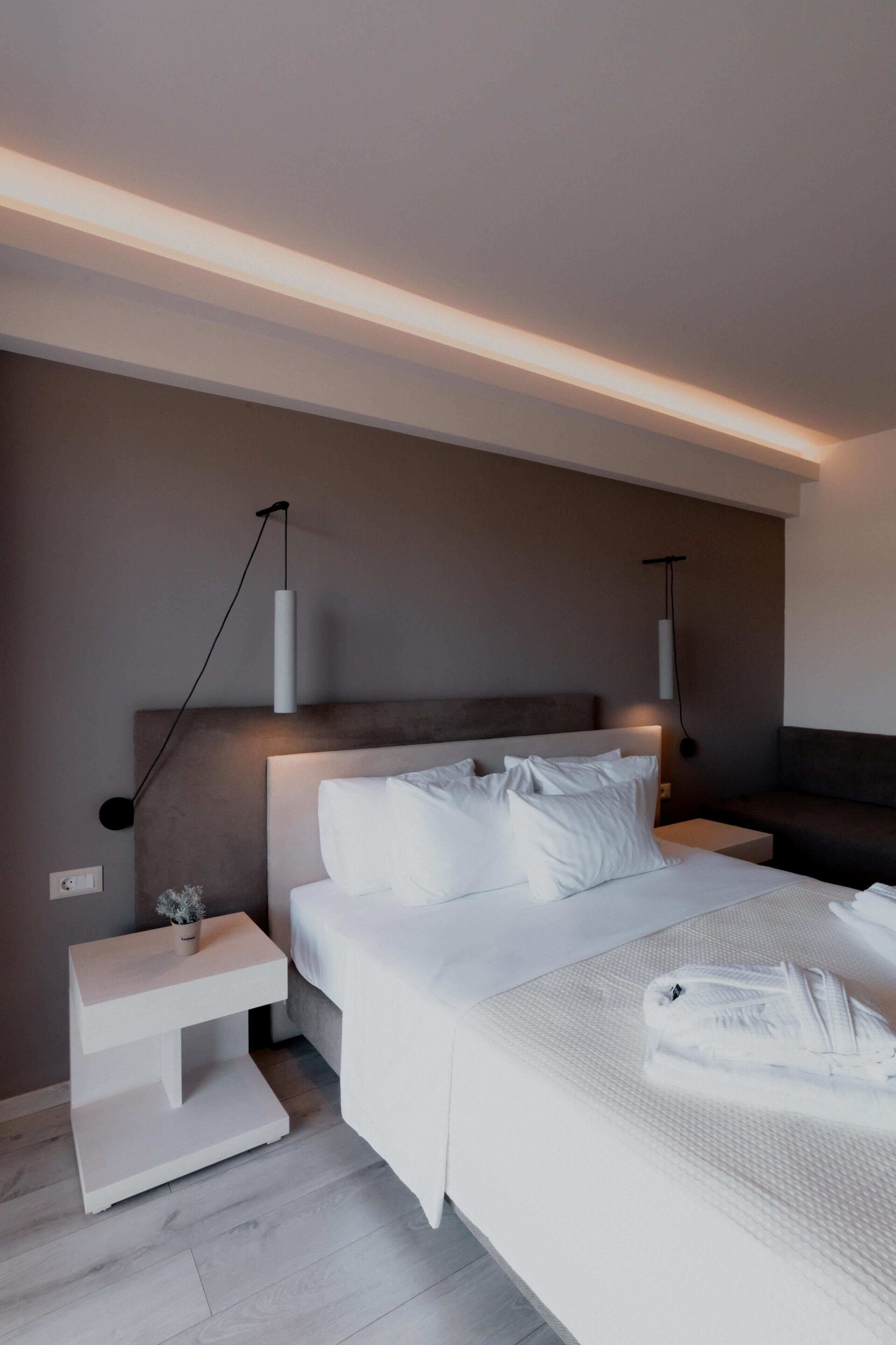 A modern bedroom with a large bed, bedside tables, and pendant lighting.