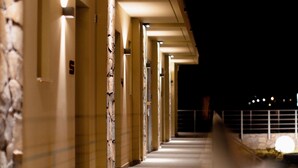 A corridor with multiple doors, each illuminated by overhead lights, leading to individual rooms. - Palacio Del Sol Luxury Apartments (Nafplio)
