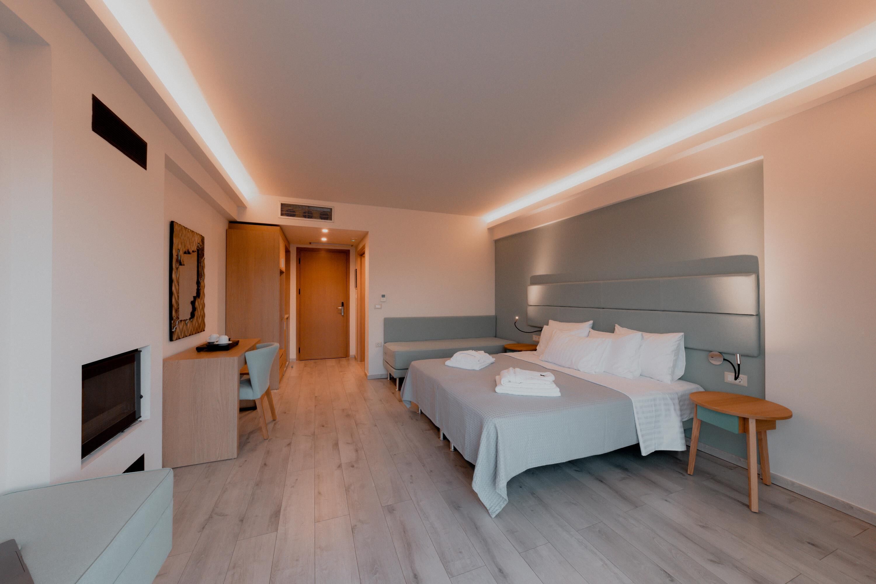 A modern hotel room with a large bed, a desk, and a TV.