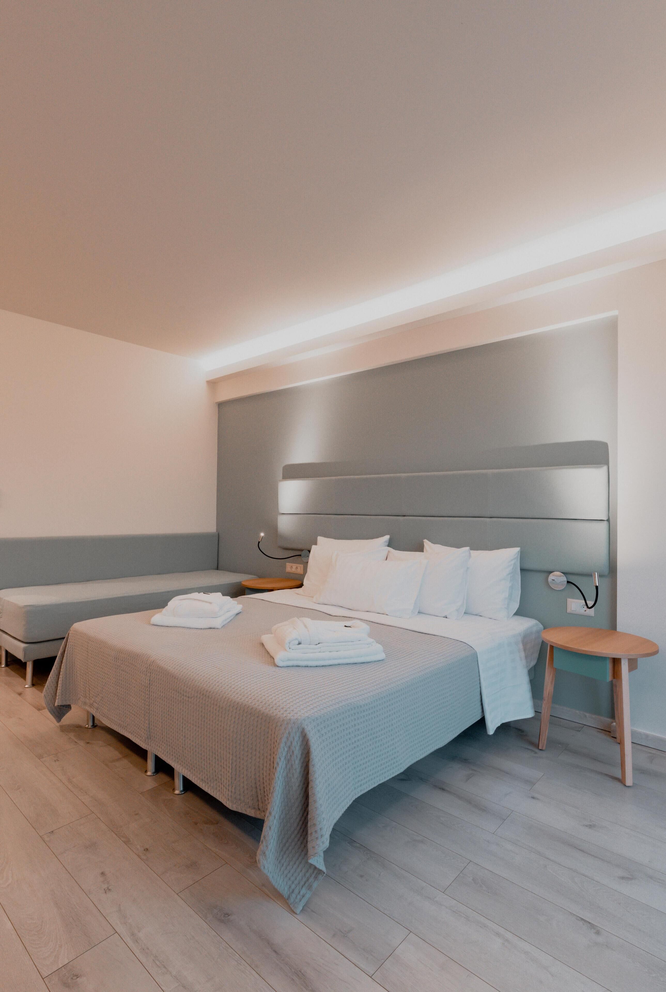 A modern hotel room with a large bed, a bedside table, and a small side table.