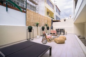 Un patio moderno al aire libre con zona de comedor, asientos y plantas en macetas.