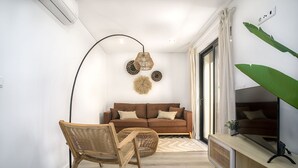 Ein modernes Wohnzimmer mit einem braunen Sofa, einem Holzstuhl, einer Stehlampe und einer großen Pflanze.