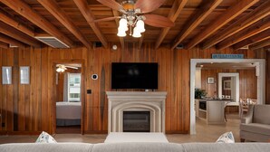 A log cabin interior with a fireplace, television, and a sofa.