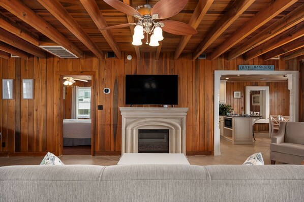 A log cabin interior with a fireplace, television, and a sofa.
