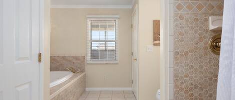 A bathroom with a bathtub, a window, and a shower area.