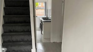A staircase leading to a kitchen area with a light-colored floor and white walls. - 4 Bedroom Lovely Home in Loughborough Town & Uni (Loughborough)