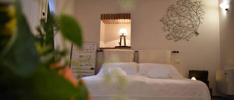 A bedroom with a bed, a wall-mounted lamp, a decorative wall piece, and a sign with text.